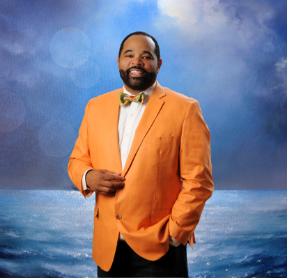 A man in an orange jacket standing on the beach.